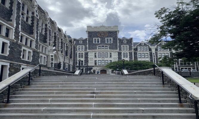 a wide concrete stairway leads up to the gothic architecture of The City College of New York.