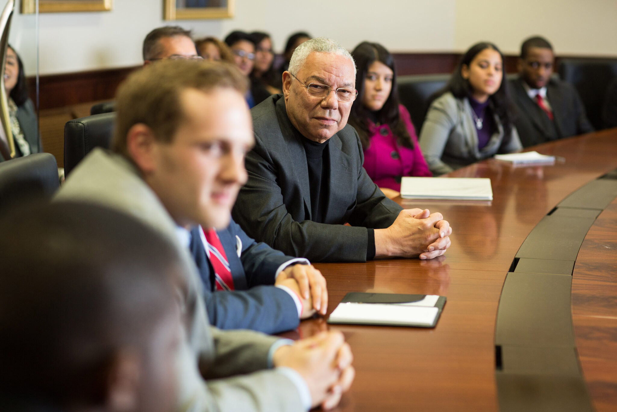 Powell sitting at a long table with CCNY students.