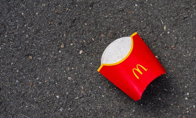 a photo of an empty large McDonald's fries box lying on the road.