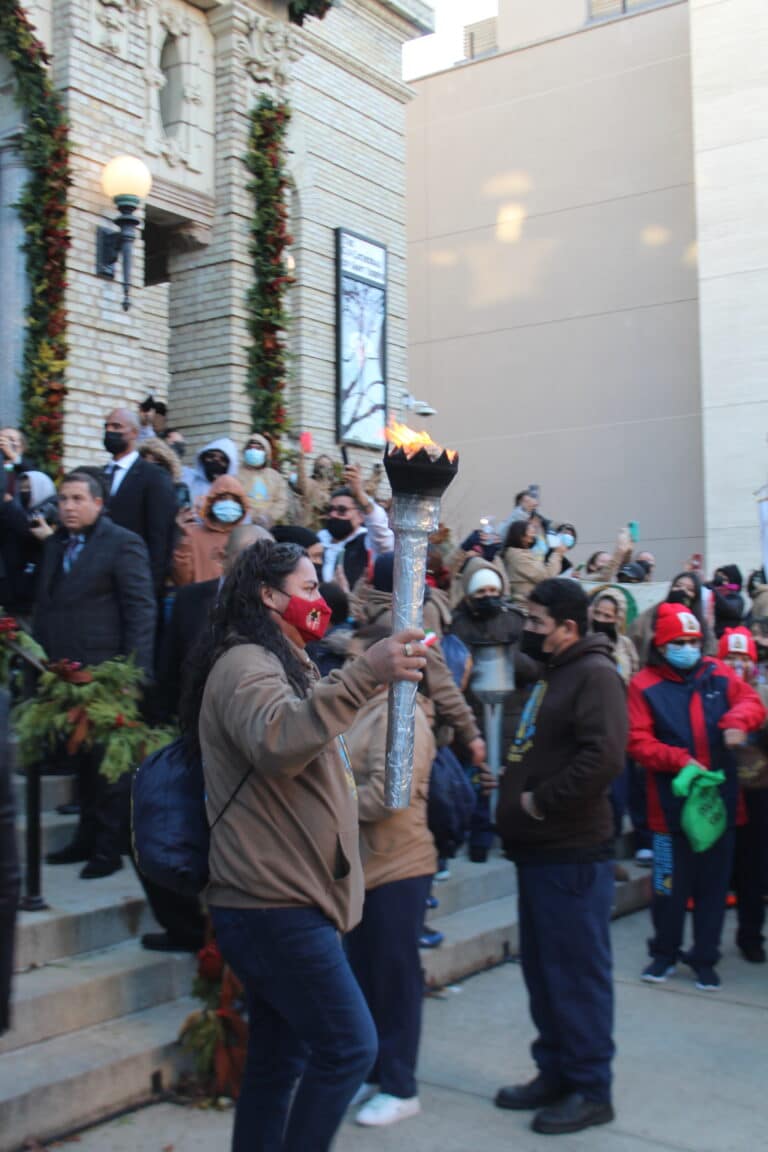 Participant from St. Matthew's church carries a torch lit by the bishop.