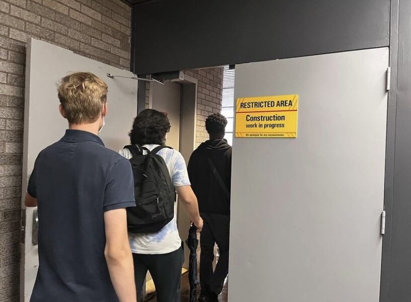 Students walking through a doorway with a sign that says "RESTRICTED AREA."