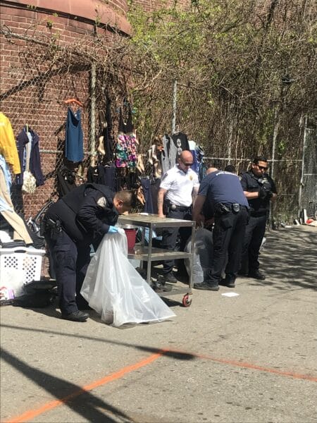 NYPD officers remove street vendor items off the streets near the Kingsbridge Armory.