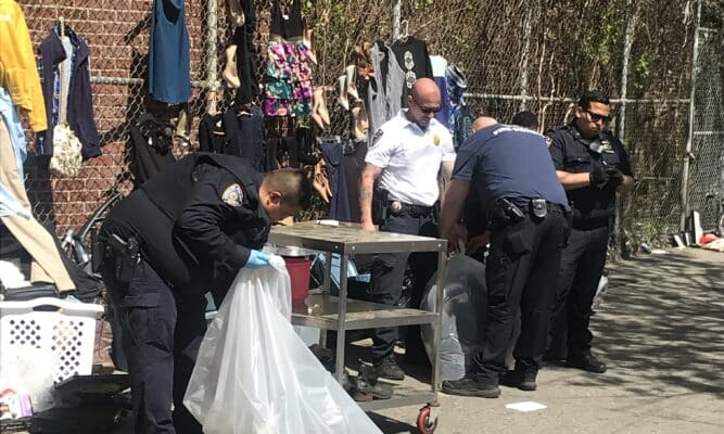 NYPD officers remove street vendor items off the streets near the Kingsbridge Armory.