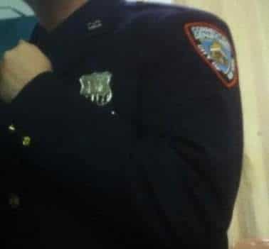 Photo of a correction officer showing his badge; face not shown to protect identity.