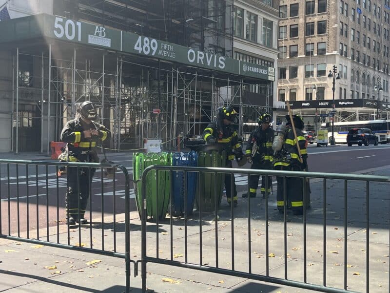 Firemen putting out a fire in a trash bin.