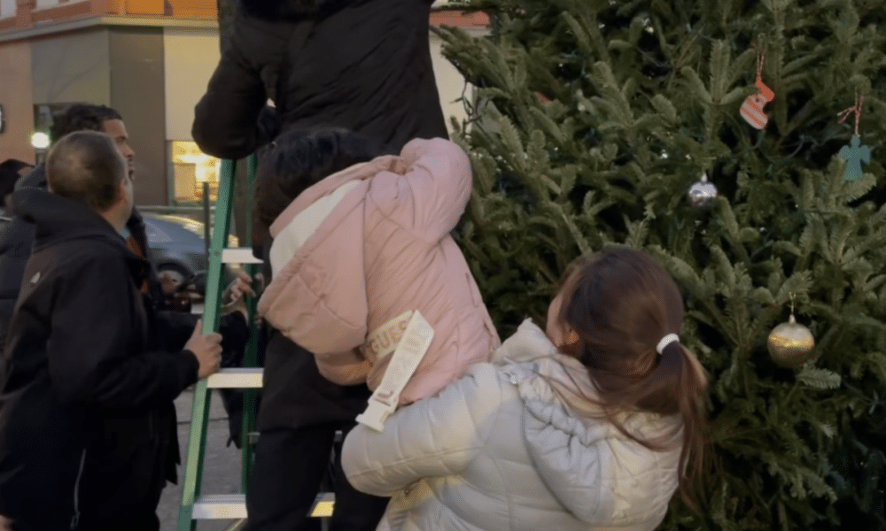 A mom holds her daughter to put Christmas decorations on a tree