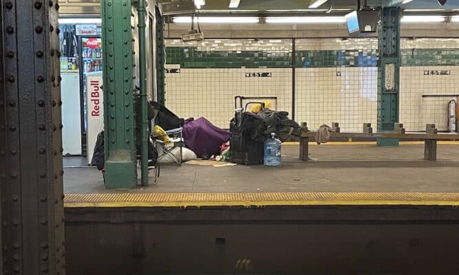 Homeless person camped out at the West 4th Street subway station.