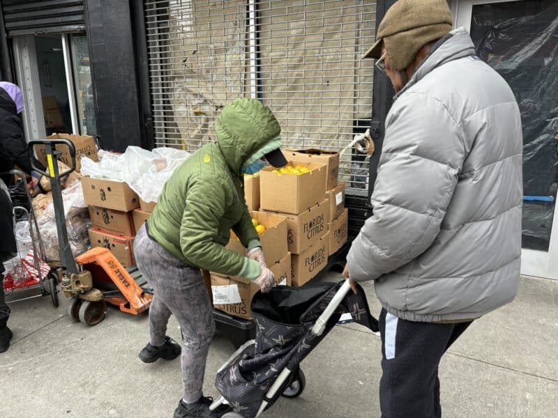 Volunteer adds produce to a local's cart.