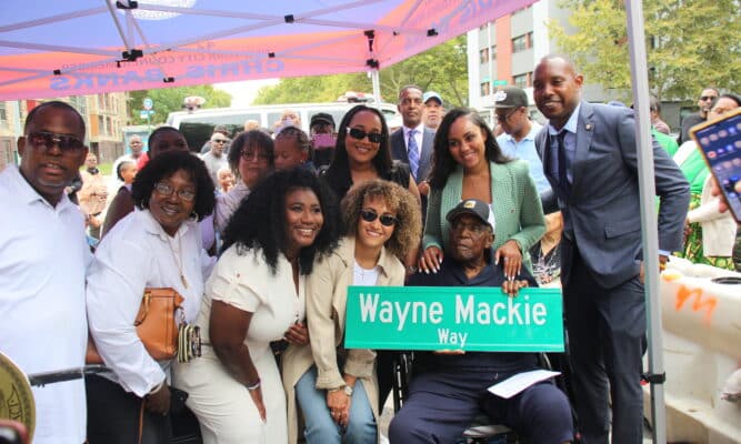 A group of people with a sign that says Wayne Mackie Way with NYC Council Member Chris Banks.