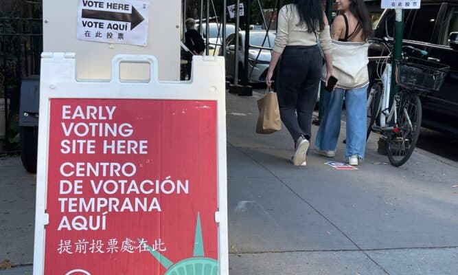 Early voting sign and people walking