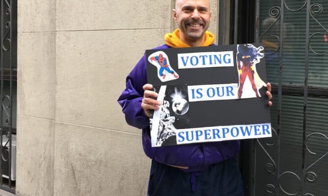 Man with sign Voting Is Our Super Power and super hero figures.