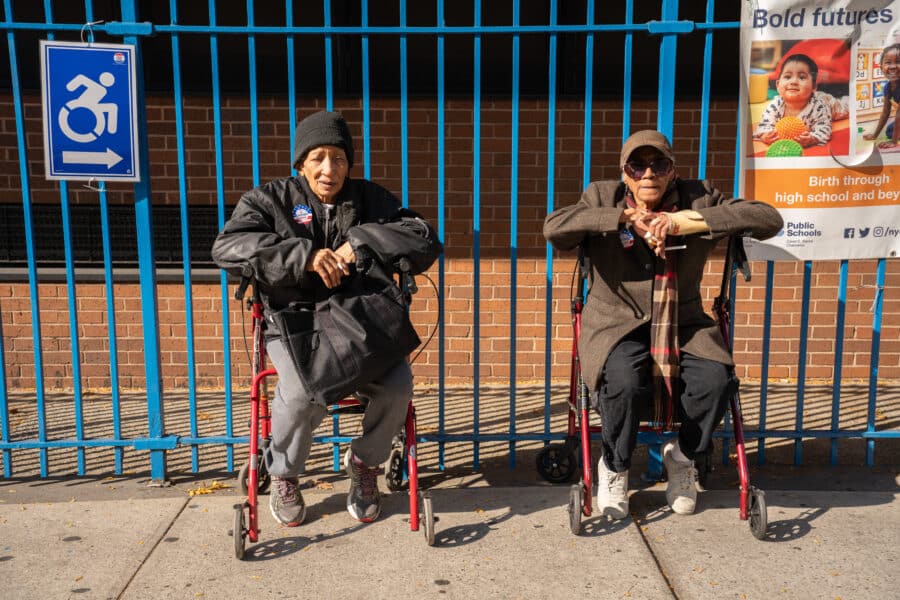 Two people sitting outside a polling place.