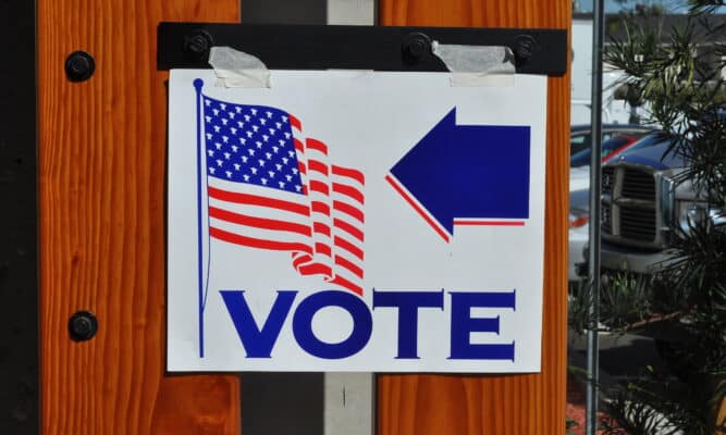 A sign that has been taped up to show the direction of where to vote.