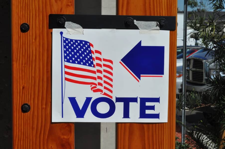 A sign that has been taped up to show the direction of where to vote.