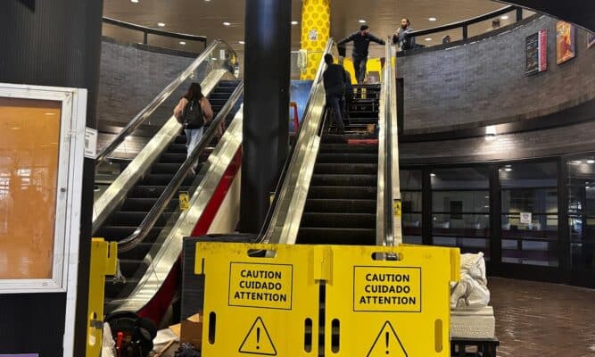 The two central escalators in NAC, the not on the right is out of service with a blockade while workers are on the top. Students are walking up the left escalators.