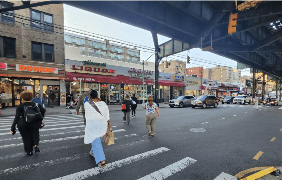 Pedestrians crossing the busy street in Marble Hill, under the elevated train tracks. 