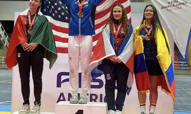 Jessica Gniedziejko proudly holds American flag up as she stands on the first place pedestal next to fellow competitors from different countries.