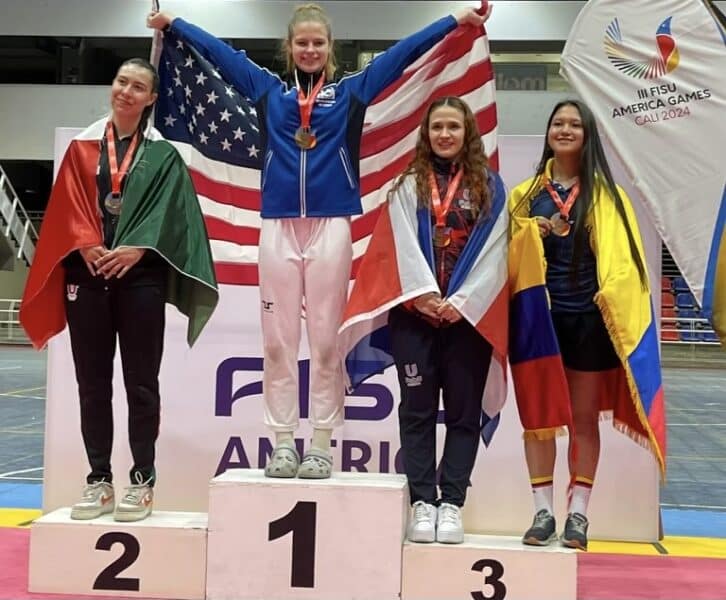 Jessica Gniedziejko proudly holds American flag up as she stands on the first place pedestal next to fellow competitors from different countries.