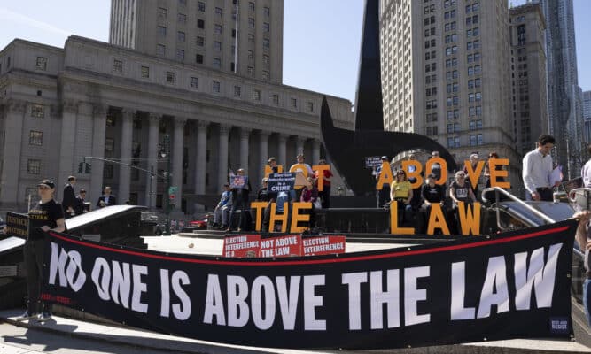 Demonstrators hold up a "no one is above the law" banner in front of a government building.