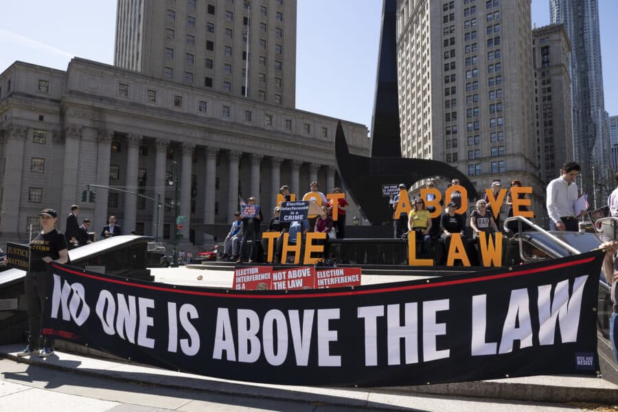 Demonstrators hold up a "no one is above the law" banner in front of a government building.