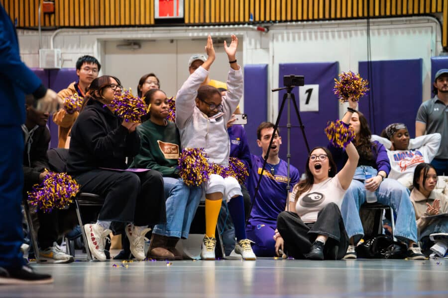 Fans cheering and waving pom-poms in celebration after victory.