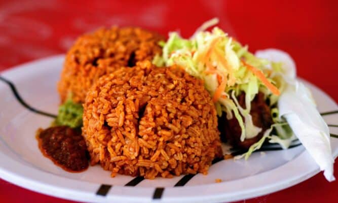 Jollof served on a plate with salad as a side.