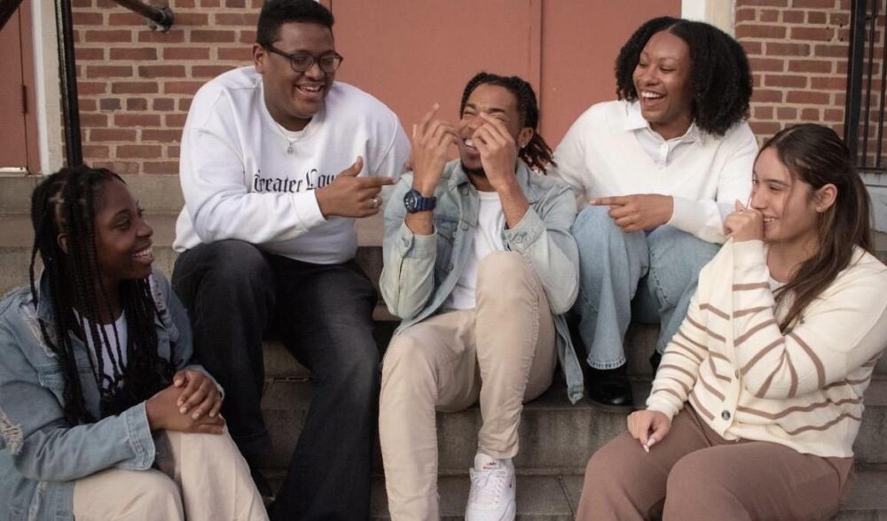 A group of people sit on steps laughing together.