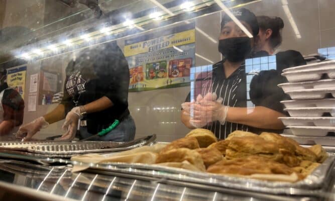 Food in a school cafeteria while cafeteria workers wait.