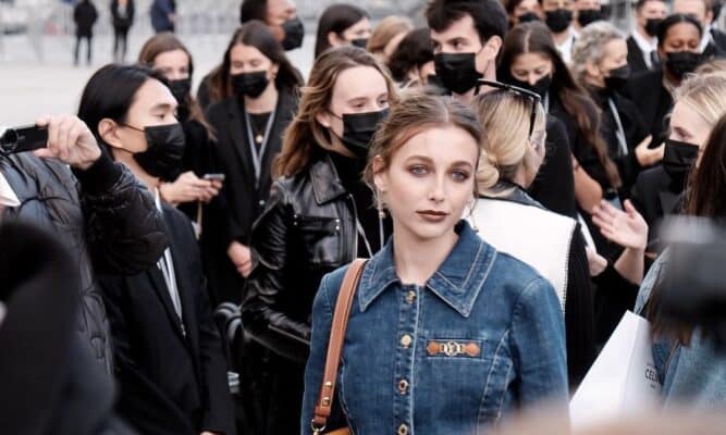 Emma Chamberlain stands in a crowd during Fashion Week