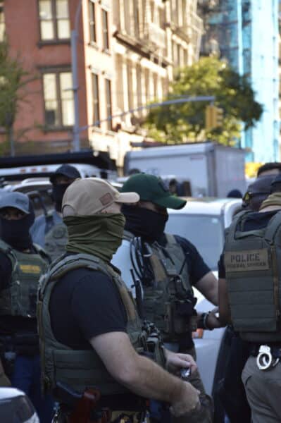 Masked federal officers, including those from Homeland Security Investigations (HSI) stand in a tactical formation near Canal Street and Centre.