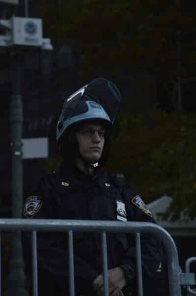 An NYPD officer a helmet stands outside 26 Federal Plaza