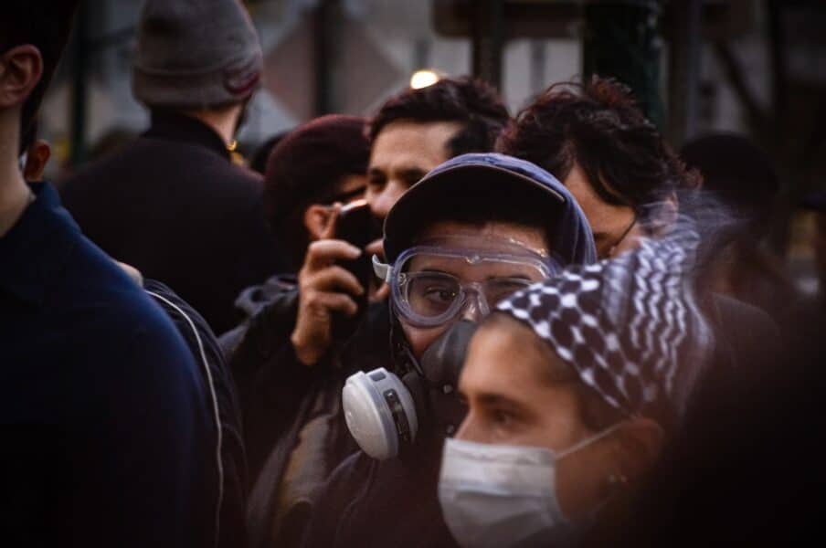 A protester with a gas mask stands with other masked protesters