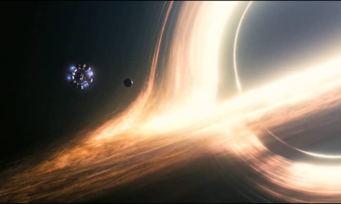 A photo of the void of outer space, on the right edge of the photo, the bright lights of the event horizon dwarf the spaceship from earth in Interstellar (2014)