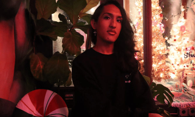 person with long hair sitting in a dimly red-lit room.