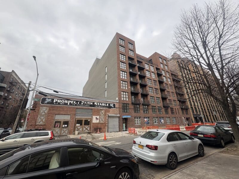 A horse stable dwarfed by luxury apartment buildings