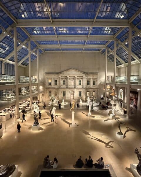 A large indoor atrium with skylights. It is filled with sculptures and observers.