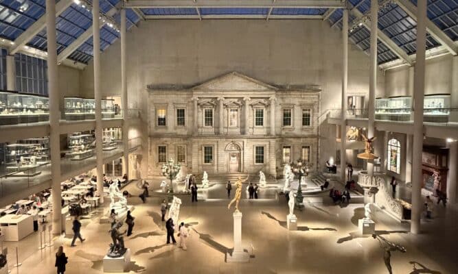 A large indoor atrium with skylights. It is filled with sculptures and observers.