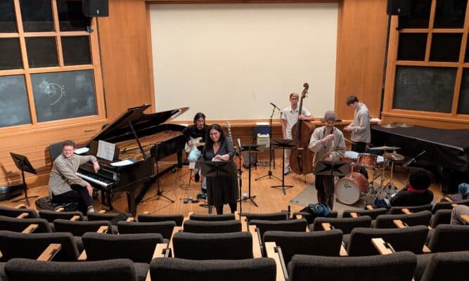 Orchestra playing a variety of instruments in a small auditorium.