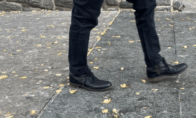 Person walking on a sidewalk filled with Gingko tree fruit on the floor