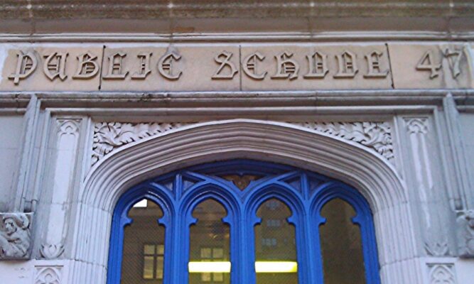 the entryway to a public school with a big blue door. the words public school appear above the door.