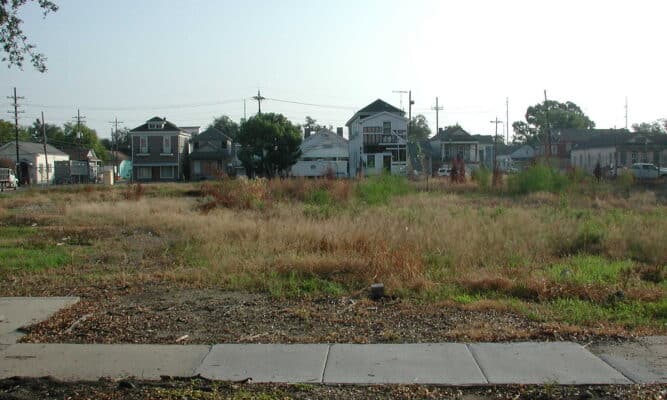Vacant, grassy lot in front of a row suburban houses.
