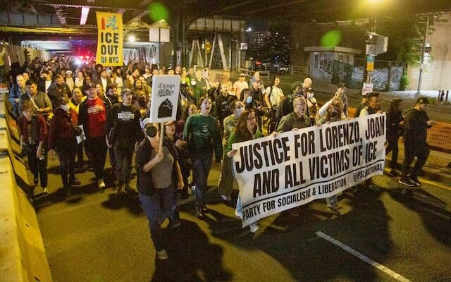 Protesters march through NYC demanding justice, holding signs.